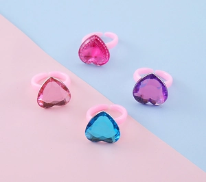 Dettaglio di anelli con gemme colorate a forma di cuore per bambine con fasce rosa