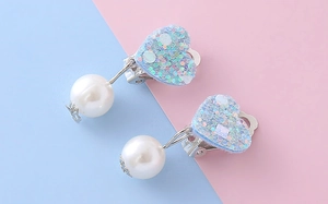 Dettaglio di clip per orecchie a cuore blu glitterato con perle bianche per bimbe