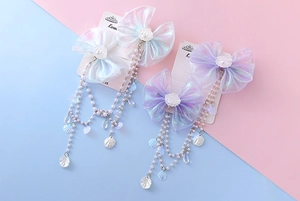 Detail of organza bow hair clip with pearl tassels and mermaid shell charm decoration