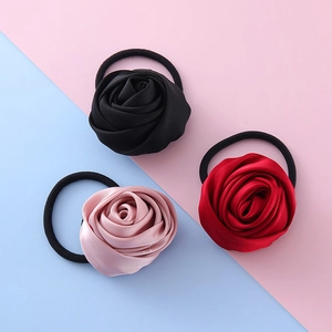 Tre elastici per capelli con rose in nero, rosso e rosa su sfondo pastello bicolore
