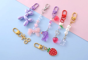 Vista piana di portachiavi colorati a forma di cane palloncino e fragola con ganci oro