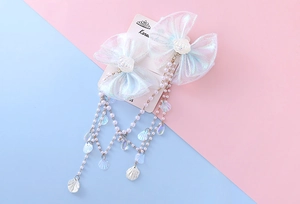 Close-up of iridescent bow hair clips with pearl tassels and shell charms for girls