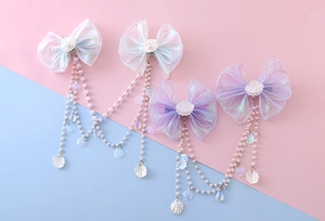 Detailed close-up of organza bow hair clips with pearls and shell tassels