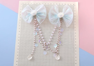 Detail of pearlescent bow hair clips with white faux pearl long tassels and shells