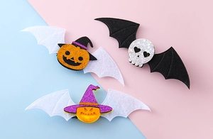 Detalle de pinzas para el pelo de Halloween con calabaza de fieltro, calavera y alas de murciélago