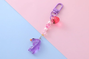 Dettaglio di un portachiavi a forma di anatra viola con perle fragola e resina