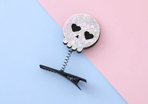 Detail of Halloween skull hair clip with white sequins and black spring on blue background