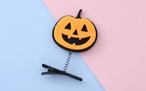 Detail of felt pumpkin hair clip with black spring and metal duckbill clip for Halloween