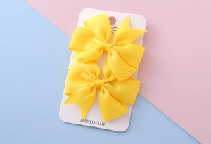 Détail de nœuds pour cheveux en ruban gros-grain jaune vif faits main sur une carte