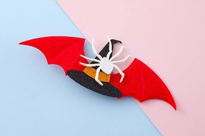 Detalle de horquilla de Halloween con alas de murciélago rojas y un sombrero de mago blanco