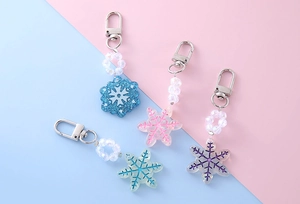 Set of four snowflake resin keychains with glitter and matte beads on pastel background