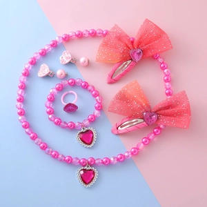 Pink heart jewelry set for kids with necklace, bracelet, ring, and clips on colorful background
