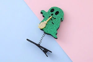 Detail of a green glitter ghost hair clip with gold broom and black spring attachment