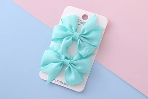 Détail de barrettes à nœuds vert menthe sur carte artisanale avec texture de ruban