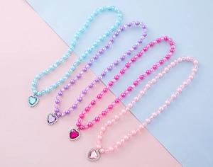 Vue macro de colliers de perles colorées avec pendentifs en cœur et faux diamants