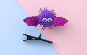 Detailed view of Halloween hair clip with purple bat wings and spring mechanism