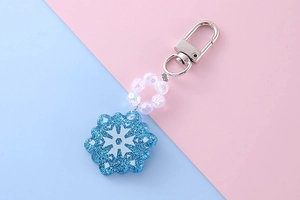 Close-up of blue glitter snowflake pendant with iridescent faceted beads on keychain