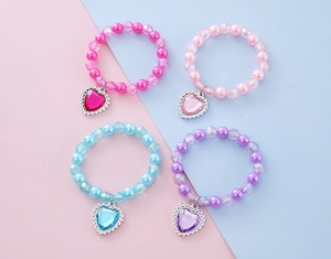 Détail de bracelets en perles colorées avec pendentifs en cœur pour petites filles
