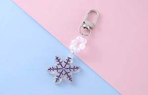Close-up of translucent purple snowflake keychain with light beads on pastel background