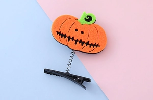 Detail view of a Halloween pumpkin spring clip featuring orange felt and black hair clip base