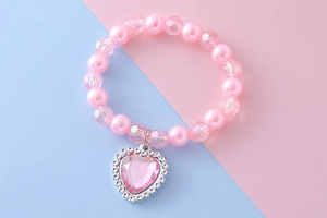 Détail de perles roses et pendentif coeur en cristal sur un bracelet style princesse
