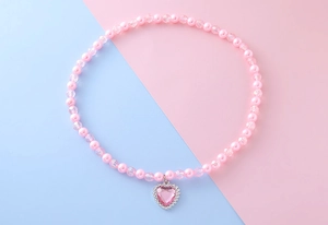 Détail du collier de perles roses pour enfants avec un pendentif en forme de cœur brillant