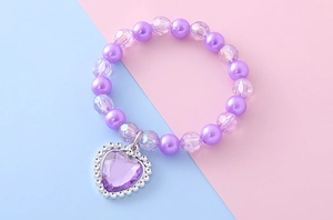 Vue détaillée des perles violettes et pendentif coeur avec pierre scintillante