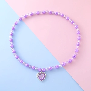 Détail du collier de perles mauves avec un pendentif étincelant en forme de cœur gemme
