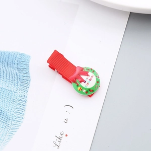 Detalle de una pinza para el pelo navideña de cinta roja con una corona festiva verde