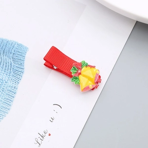 Detalle de la pinza para el pelo navideña con campanas amarillas y lazo rojo sobre tarjeta