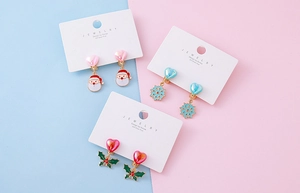 Three pairs of Christmas theme clip-on earrings with Santa, snowflake and holly motifs
