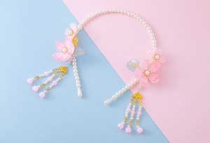 Close-up of pink resin flower hairband with white pearls and long beaded tassel detail