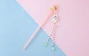Close-up of pink hair stick with sakura charm, pearls and green teardrop tassel detail