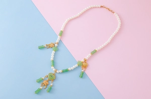 Macro view of Chinese style pearl necklace with green bamboo beads and gold tassels