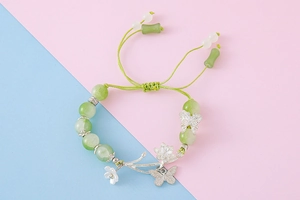 Detail of beaded bracelet with green jade-like stones and silver butterfly charms