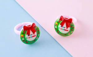 Detailed close-up of a pink resin Christmas wreath ring with a festive red bow and text