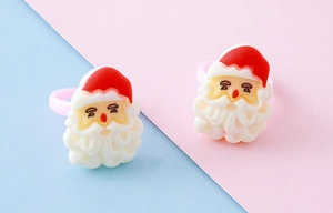 Close-up of cute 3D resin Santa Claus rings with red hats and pink bands for Christmas