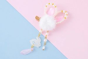 Detail of flower hair clip with white plush pompom, pearl rabbit ears and pink tassel charm
