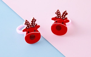 Detailed view of red reindeer resin rings with adjustable pink bands on pastel background