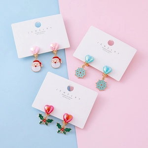 Three pairs of Christmas clip-on earrings featuring Santa, snowflakes, and holly for kids