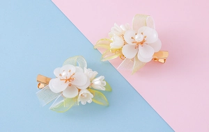 Detail view of pearlized white flower hair clips with soft resin leaves and ribbon
