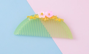 Detail of traditional hair comb with gold floral filigree and pink blossom accents