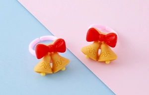 Close-up of adjustable resin Christmas rings featuring yellow bells and a red bow