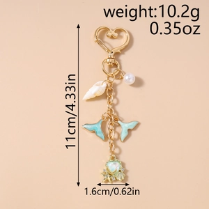 Detail of a gold starfish heart shell keychain with blue fish tail and faux pearl