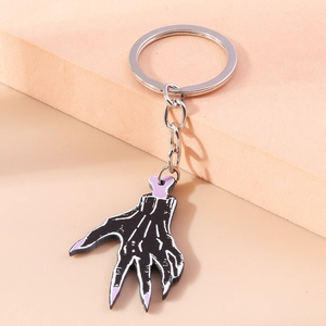 Detail view of cartoon demon skull palm keychain with purple accents and silver ring