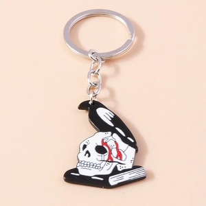 Detail of metal crow perched on skull and book keychain with silver ring and chain
