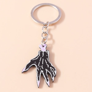 Detail view of zombie hand keychain with black skin, white bones and purple nails