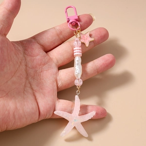 Detail of pink resin starfish keychain with glitter filling and striped beads