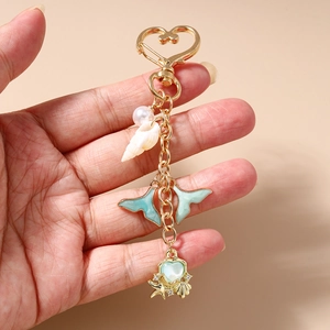 Detail of starfish and shell charms on a gold heart-shaped keychain with pearls