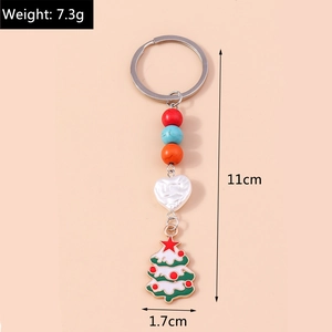 Detail of Christmas tree keychain with colorful beads and white heart on pink background